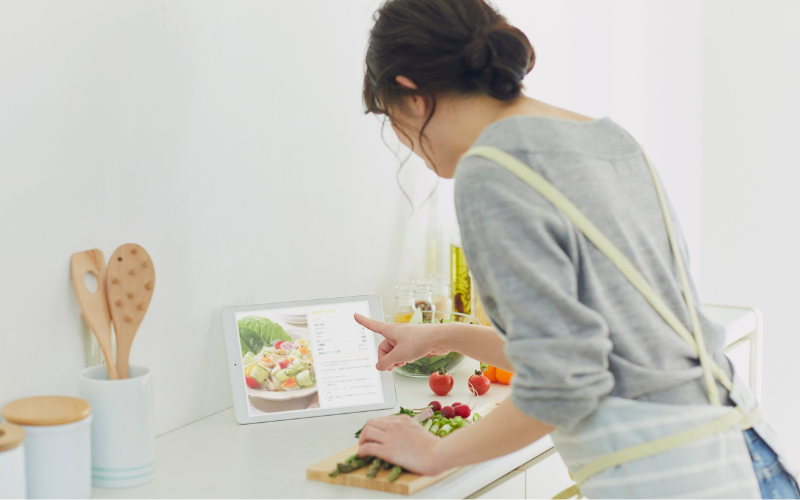 レシピを見ながら料理する売女性の後ろ姿